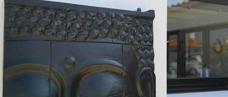 Suuri, tummanvärinen Buddha-patsas on kiinnitetty seinään, ja sen yläpuolella on pieni ikkuna.