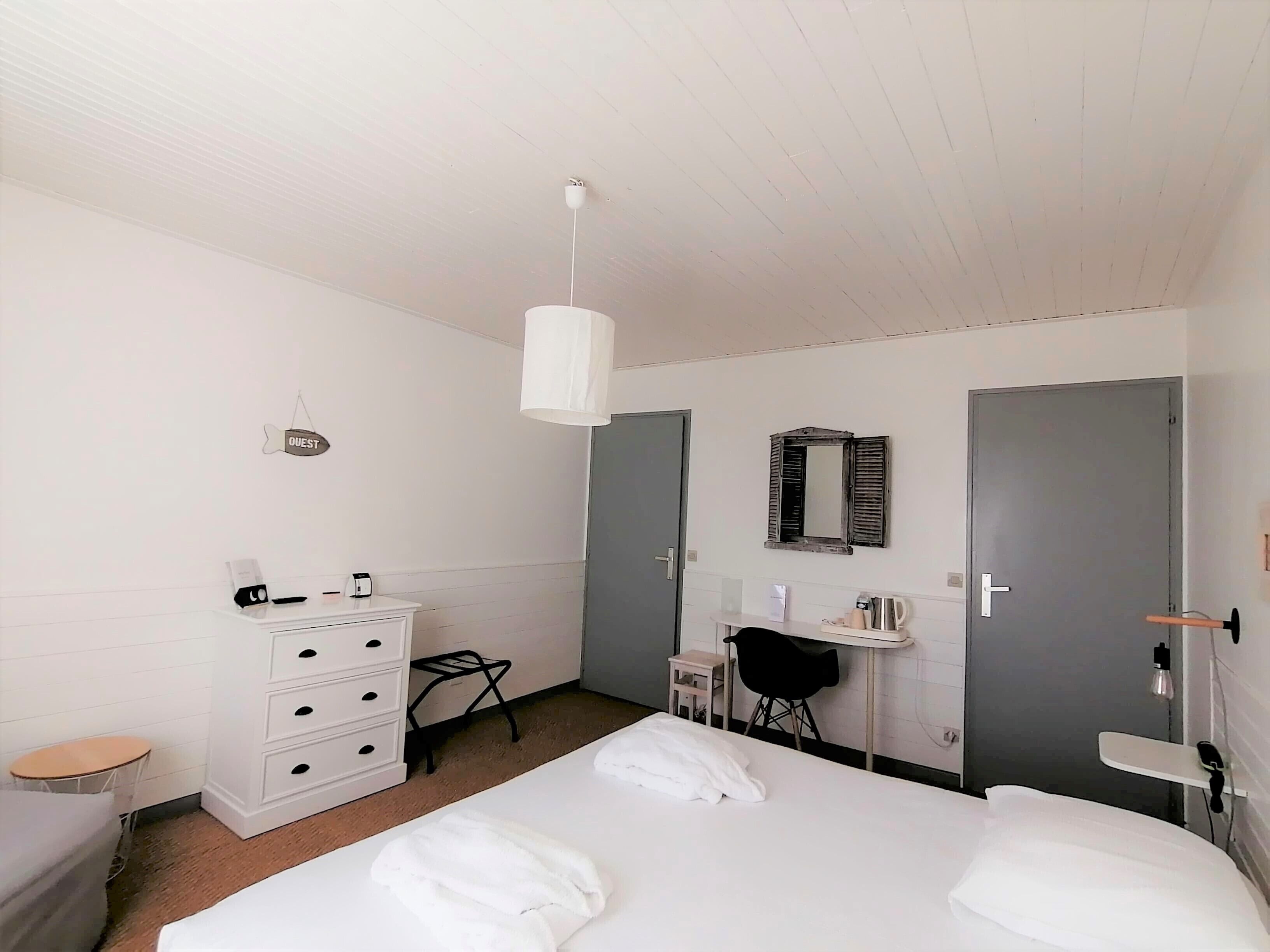 A bedroom with a bed, a dresser, a desk, a chair, a mirror, and a door.