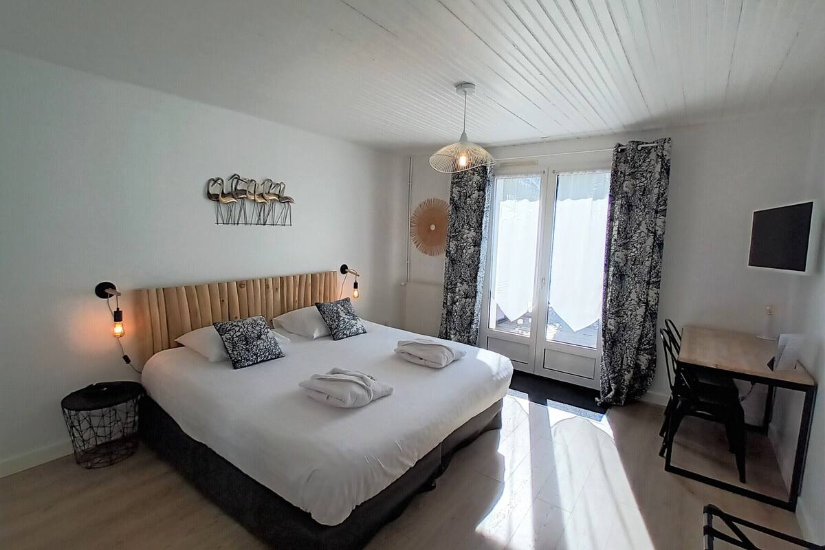 A modern bedroom with a large bed, bedside lamps, a desk, and a chair.