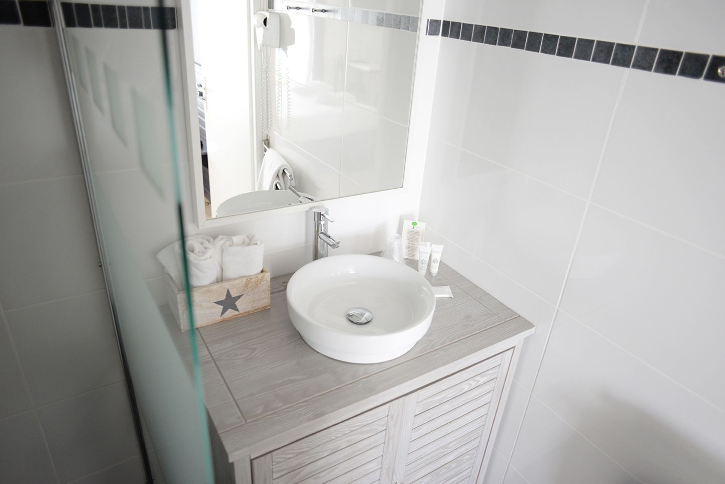 A modern bathroom with a white sink, a mirror, and a wooden vanity.