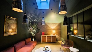 A cozy room with a red sofa, a wooden cabinet, a plant, and hanging pendant lights.