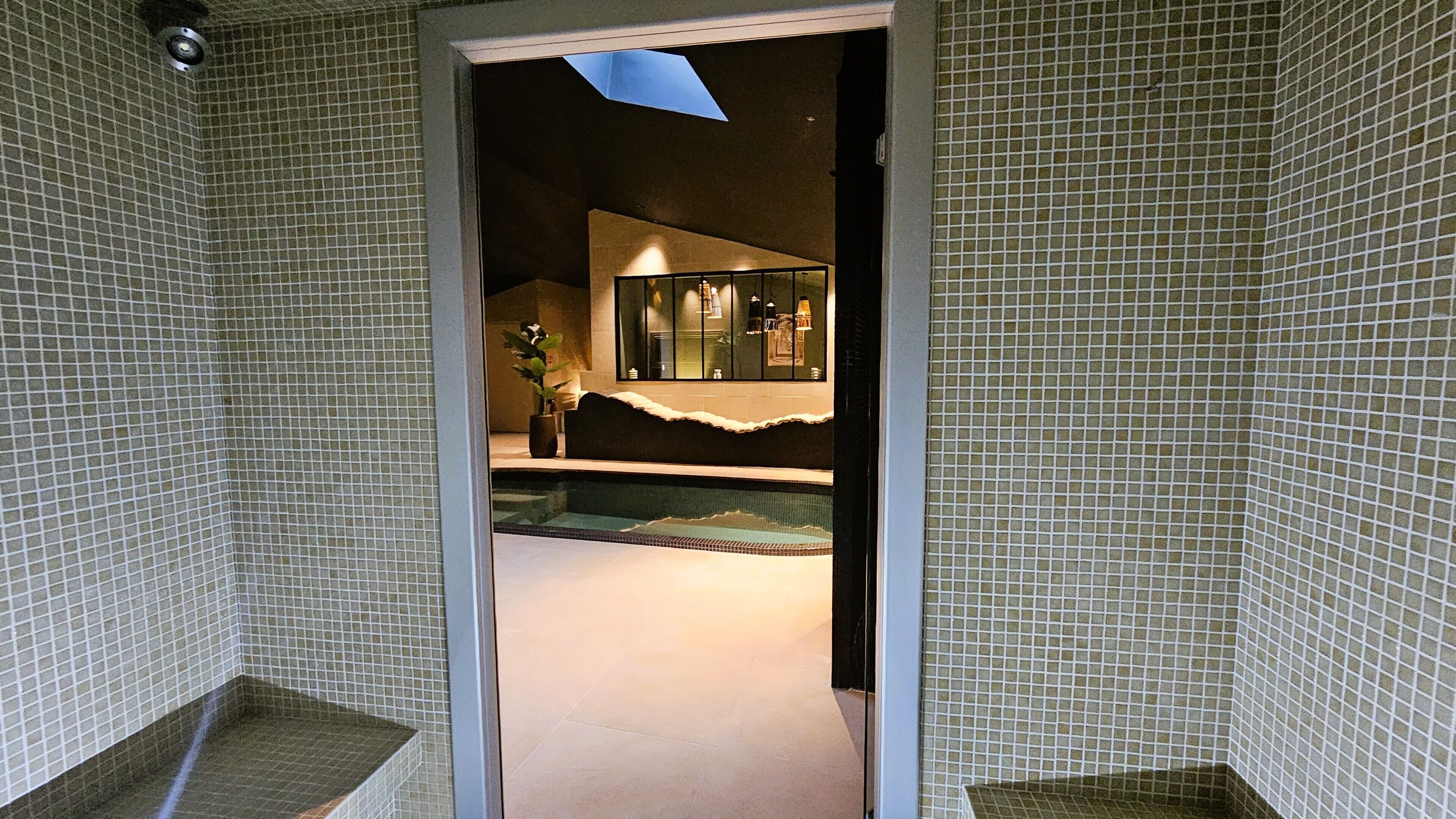 A bathroom with tiled walls, a shower area, and a sink.