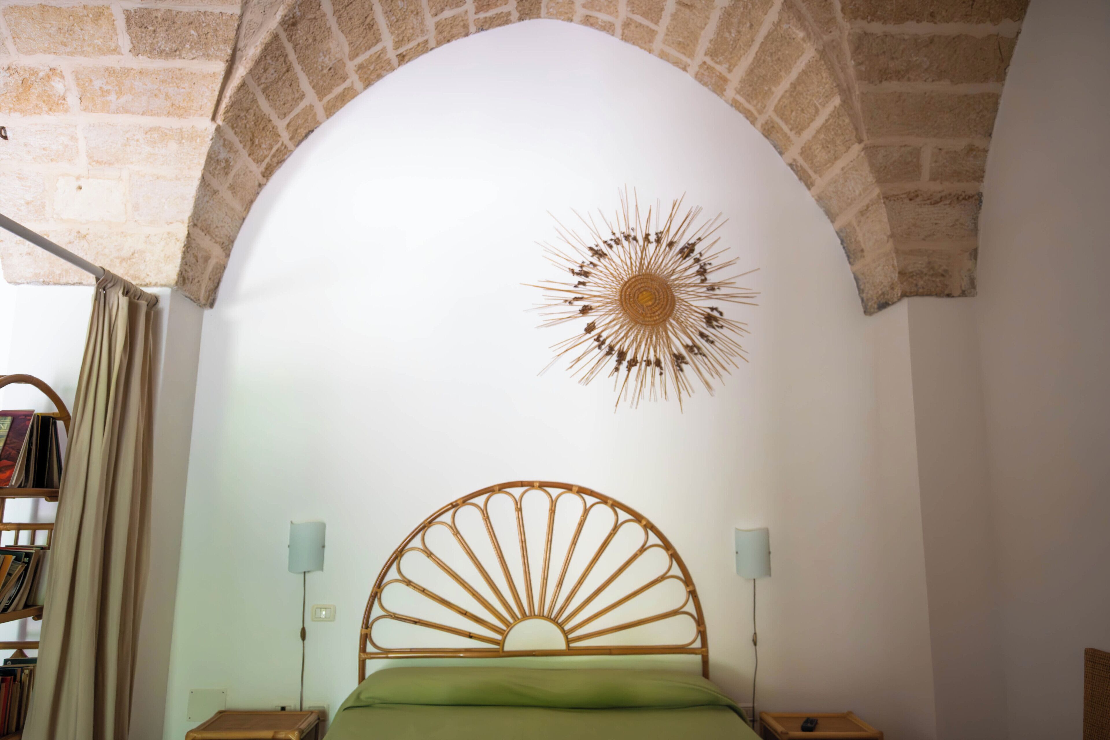Una camera da letto con un letto sotto un soffitto a volta, un elemento decorativo a parete e una libreria.