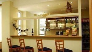 Una zona de bar con sillas de madera y un estante lleno de botellas.