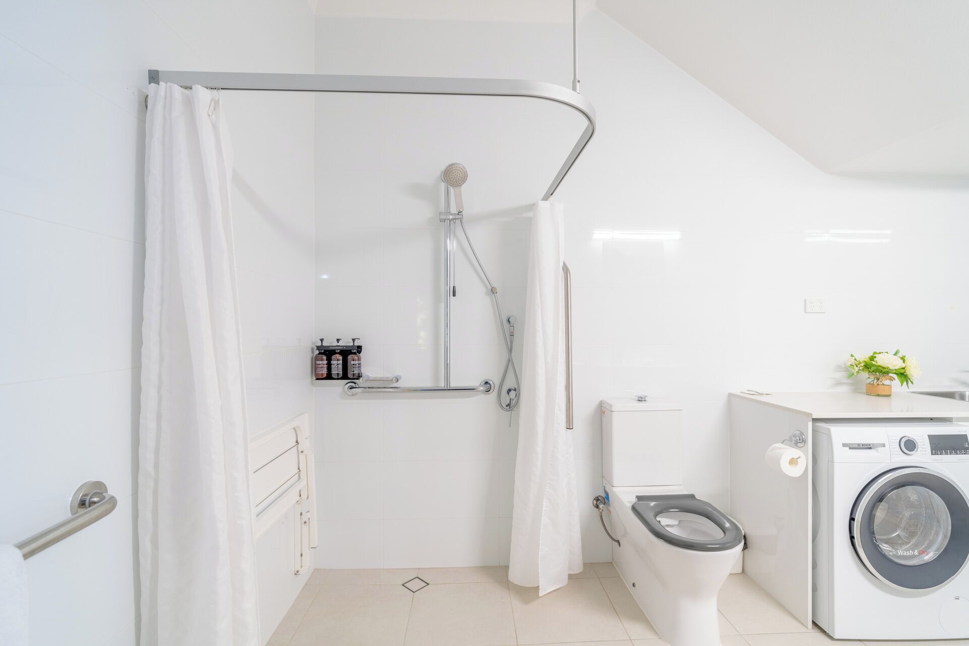 A modern bathroom with a shower, toilet, and washing machine.