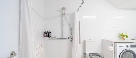 A modern bathroom with a shower, toilet, and washing machine.