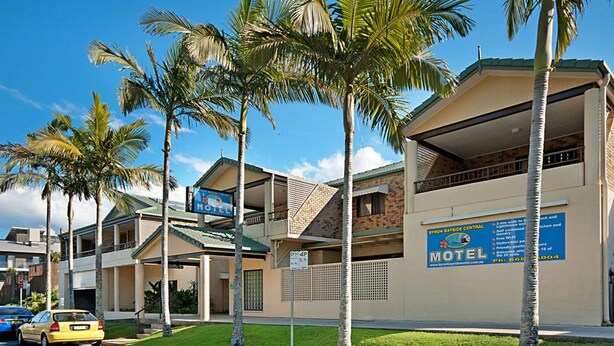 A motel with a signboard, a parking area, and palm trees. - Byron BaySide Central Studio Apartments (Byron Bay)