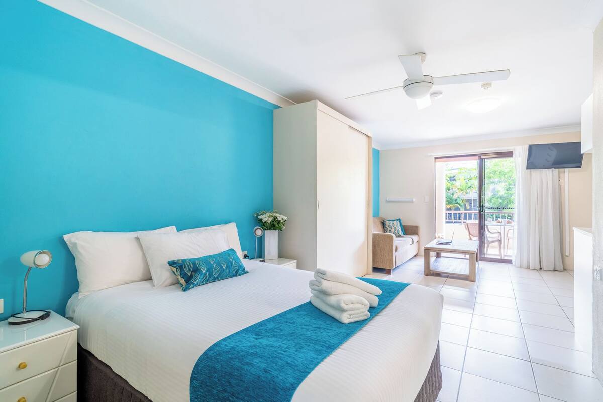 Una habitación de hotel con cama, escritorio, silla y televisor.