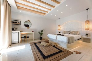 A modern bedroom with a bed, bedside tables, a desk, a refrigerator, and a potted plant. - Aegean Land (Naxos)