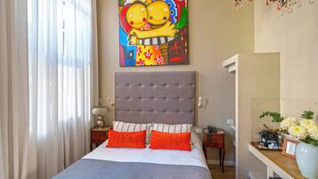 Un dormitorio con una cama grande, un cabecero, una mesita de noche, una lámpara, un espejo y un cuadro en la pared.
