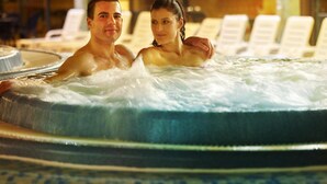 A couple in a hot tub with lounge chairs in the background.