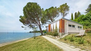 A modern house by a lake with a clear view of the water and sailboats.