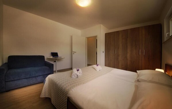 Une chambre d’hôtel avec un lit, un canapé, une petite table et une armoire.