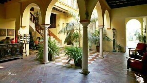 Un interior espacioso con suelo a cuadros, múltiples arcos y plantas en macetas.