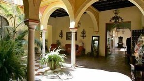 Un interior espacioso con techos altos, arcos y un área central abierta con una fuente.