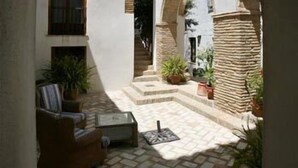 Un patio con zona de estar, una escalera y plantas en macetas.