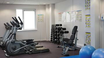 A gym with treadmills, dumbbells, and exercise balls.