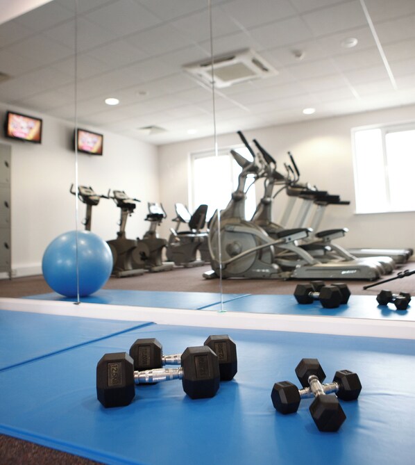 A gym with exercise equipment, including dumbbells, a blue mat, and treadmills. - Leonardo Hotel Bradford (Bradford)