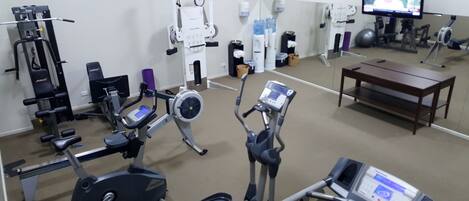 A gym with various exercise equipment including treadmills, stationary bikes, and weight machines.