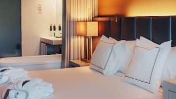 Une chambre d’hôtel comprenant un lit, des oreillers, une table de chevet, une lampe, ainsi qu’une salle de bain avec un lavabo et des articles de toilette.