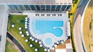 Vue aérienne d’un hôtel doté d’une piscine, entourée de chaises longues et de tables.