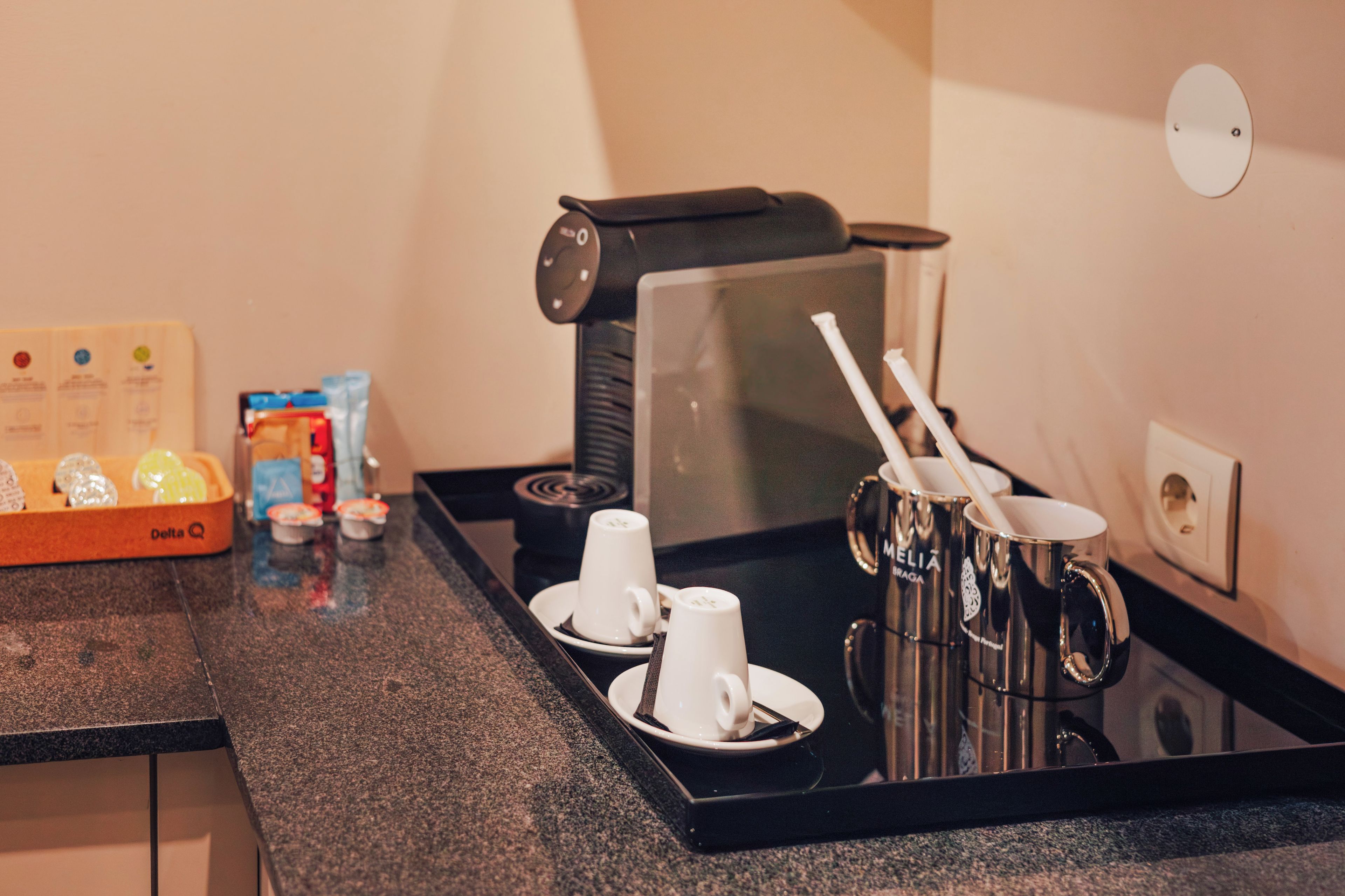 Cantinho de café com máquina de café, xícaras e bandeja.
