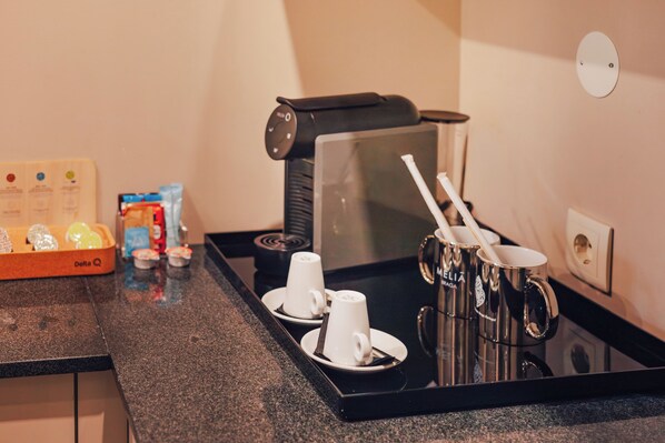 A coffee station with a coffee machine, cups, and a tray.