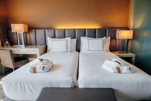 Een hotelkamer met twee bedden, een bureau, twee lampen en een stoel.