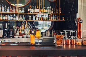 Un espace bar avec un assortiment de bouteilles et de verres, un robinet et un plateau sur lequel se trouve un cocktail.