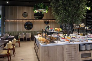 Ein Bereich mit Buffet und vielfältigen Speisen sowie eine Sitzgelegenheit mit Stühlen und Tischen.
