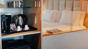 A hotel room with a bed, a coffee station, and a minibar.