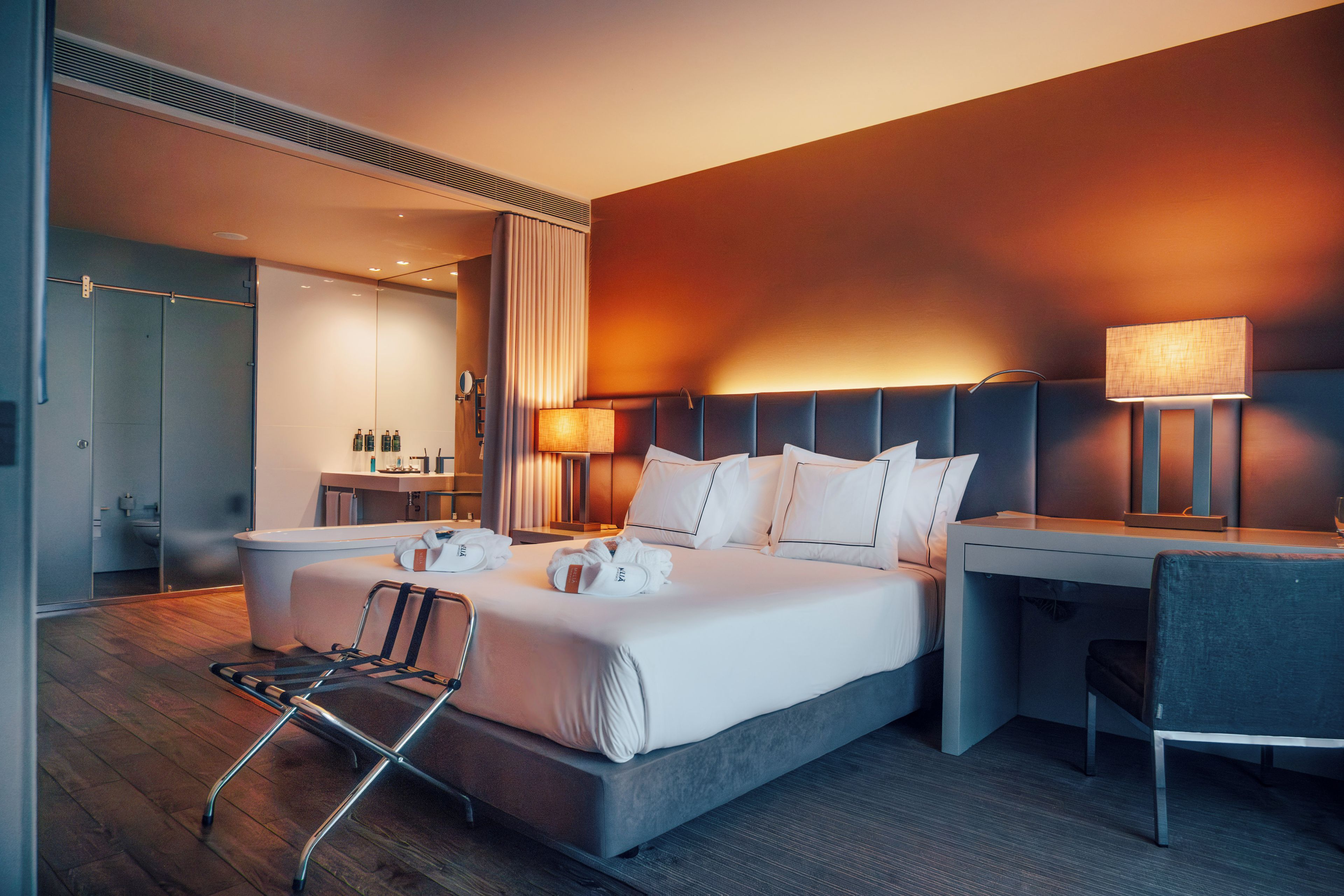 Una habitación de hotel moderna con una cama grande, mesitas de noche, un escritorio y una silla.