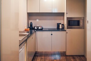 Une cuisine compacte équipée d’un four à micro-ondes, d’une machine à café et d’un petit évier.