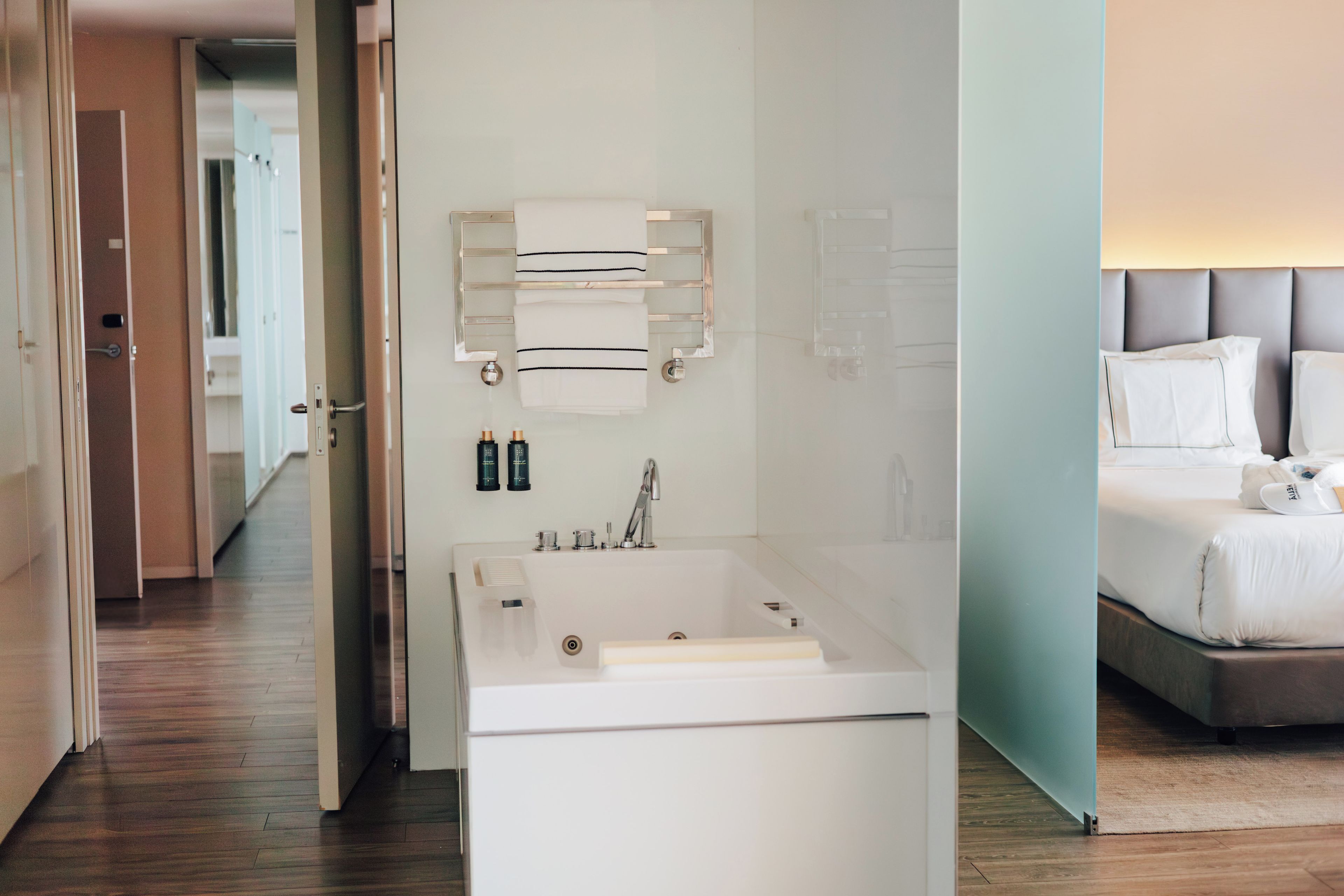 A modern bathroom with a bathtub, a mirror, and a towel rack.