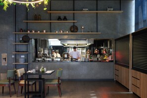 A modern kitchen with a bar area, wooden shelves, and a dining table with chairs. - Melia Braga Hotel & Spa (Braga)