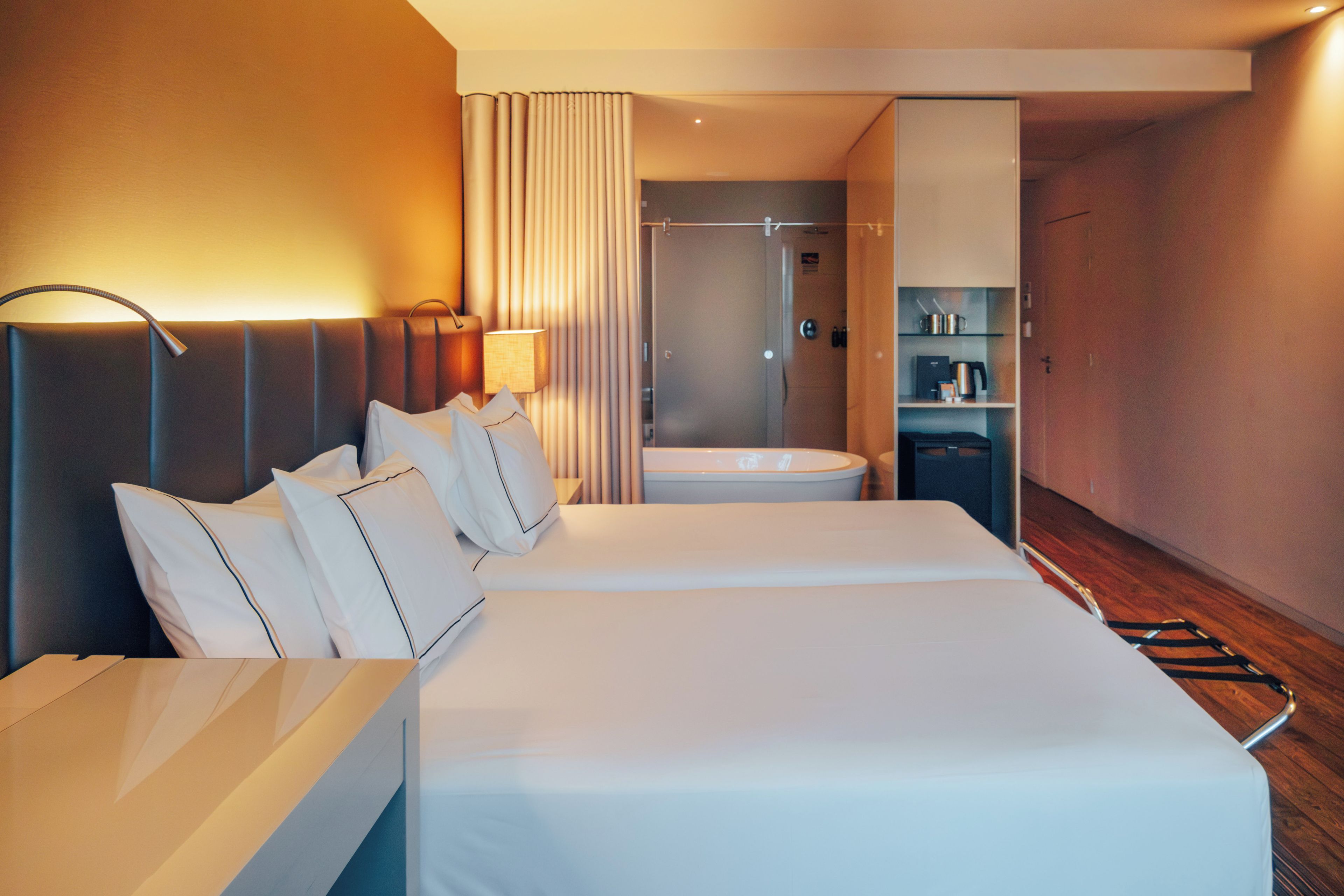 A hotel room with two beds, a bathroom, and a minibar.