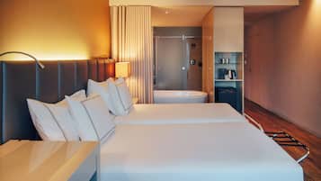 A hotel room with two beds, a bathroom, and a minibar.