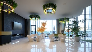 Un hall d’entrée moderne avec un grand téléviseur, des meubles blancs et des plantes suspendues.