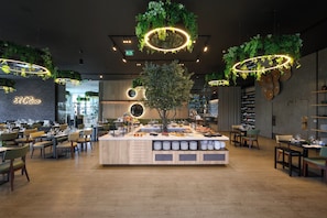 Un restaurant doté d’un îlot central, de plusieurs espaces de restauration et d’une variété de plantes et d’éléments d’éclairage.