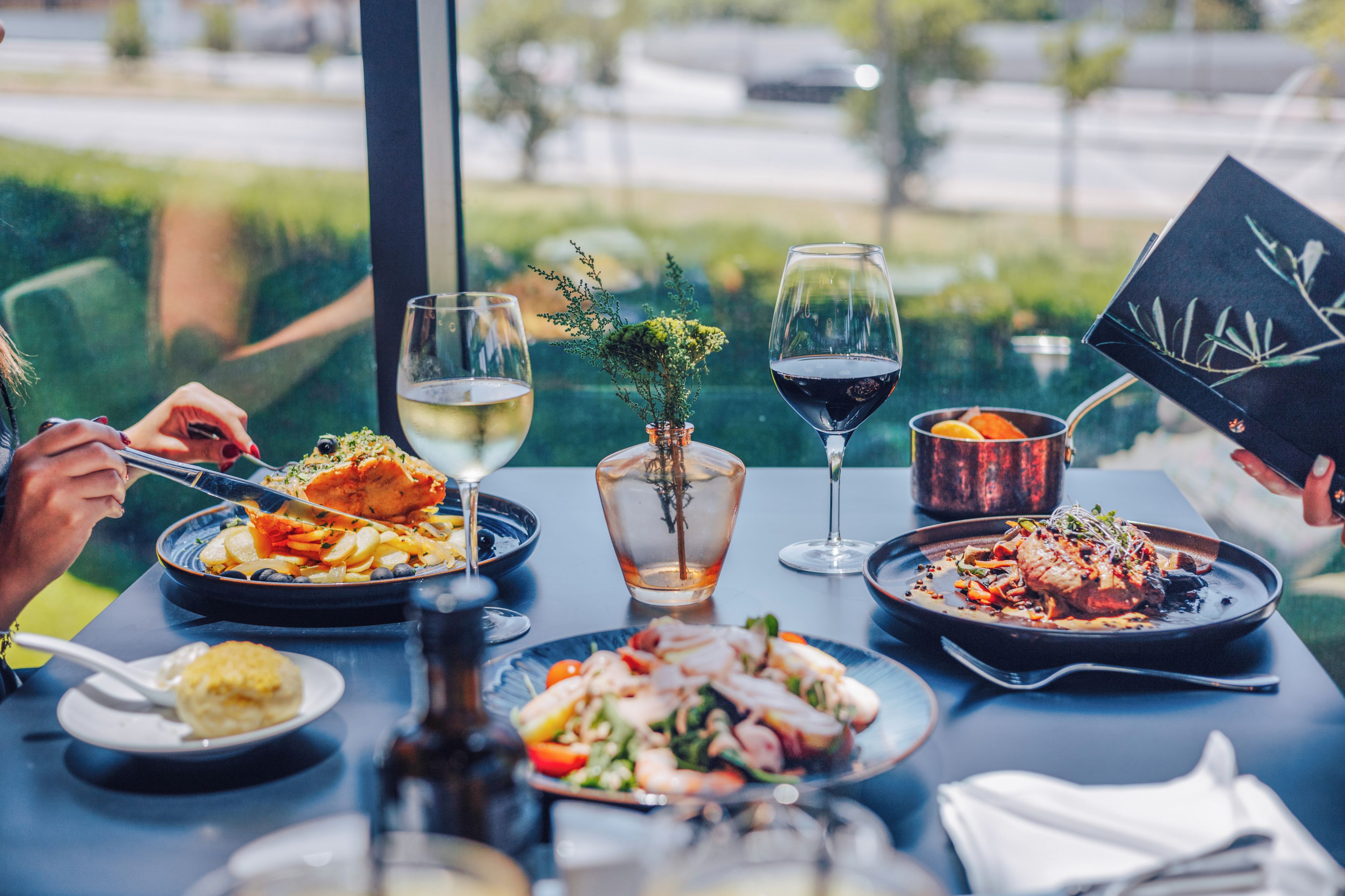 Une table à manger avec différents plats, des verres de vin et un menu.