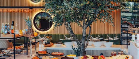 Un buffet garni de divers plats, agrémenté d’un miroir et d’une composition florale en forme d’arbre.