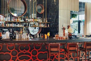 Un espace bar doté de plusieurs étagères remplies de bouteilles, d’un comptoir et de tabourets de bar.