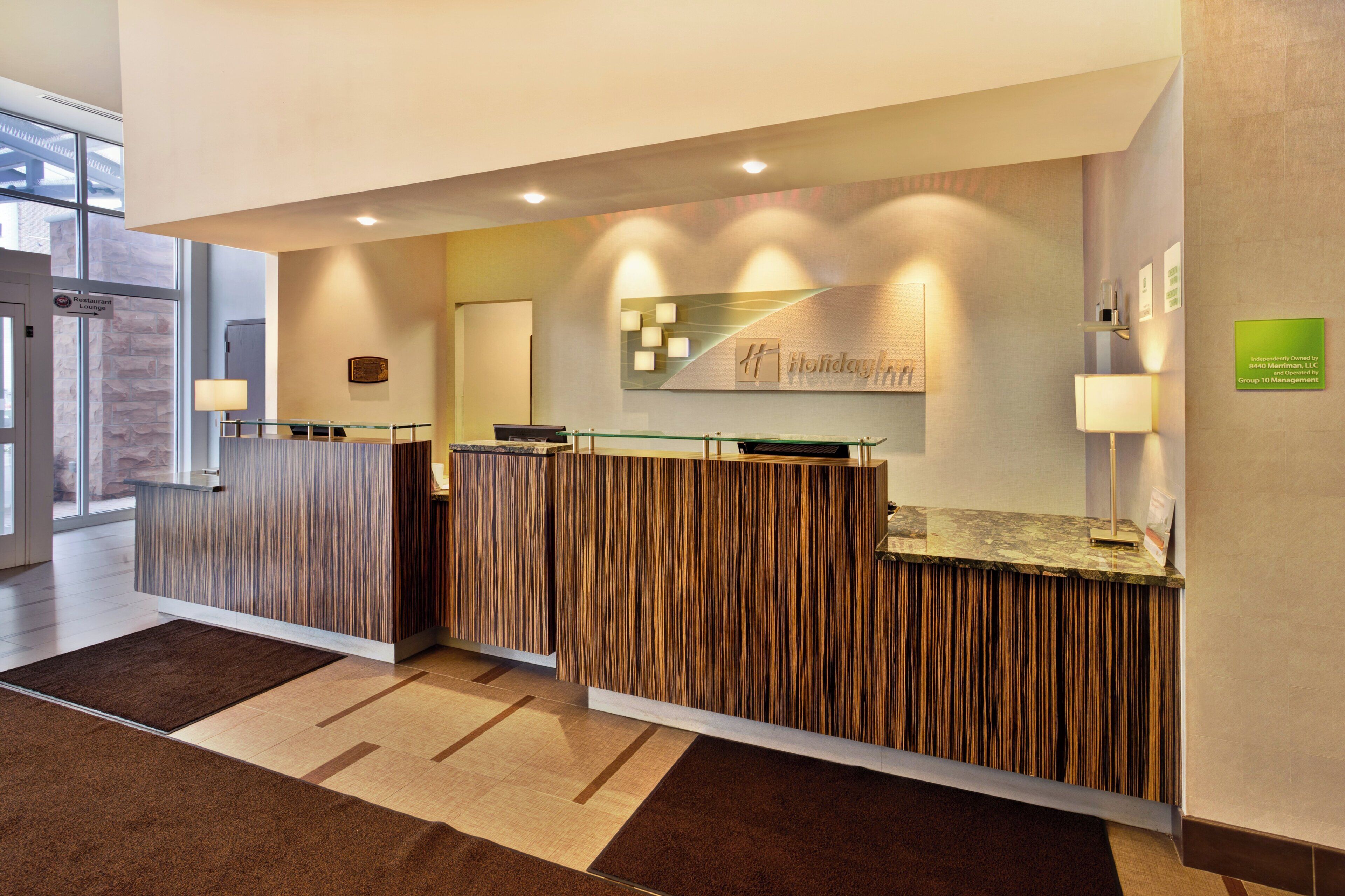 Un'area reception di un hotel dal design moderno, con una scrivania della reception, un cartello per il lounge ristorante e il logo Holiday Inn Express sul muro.