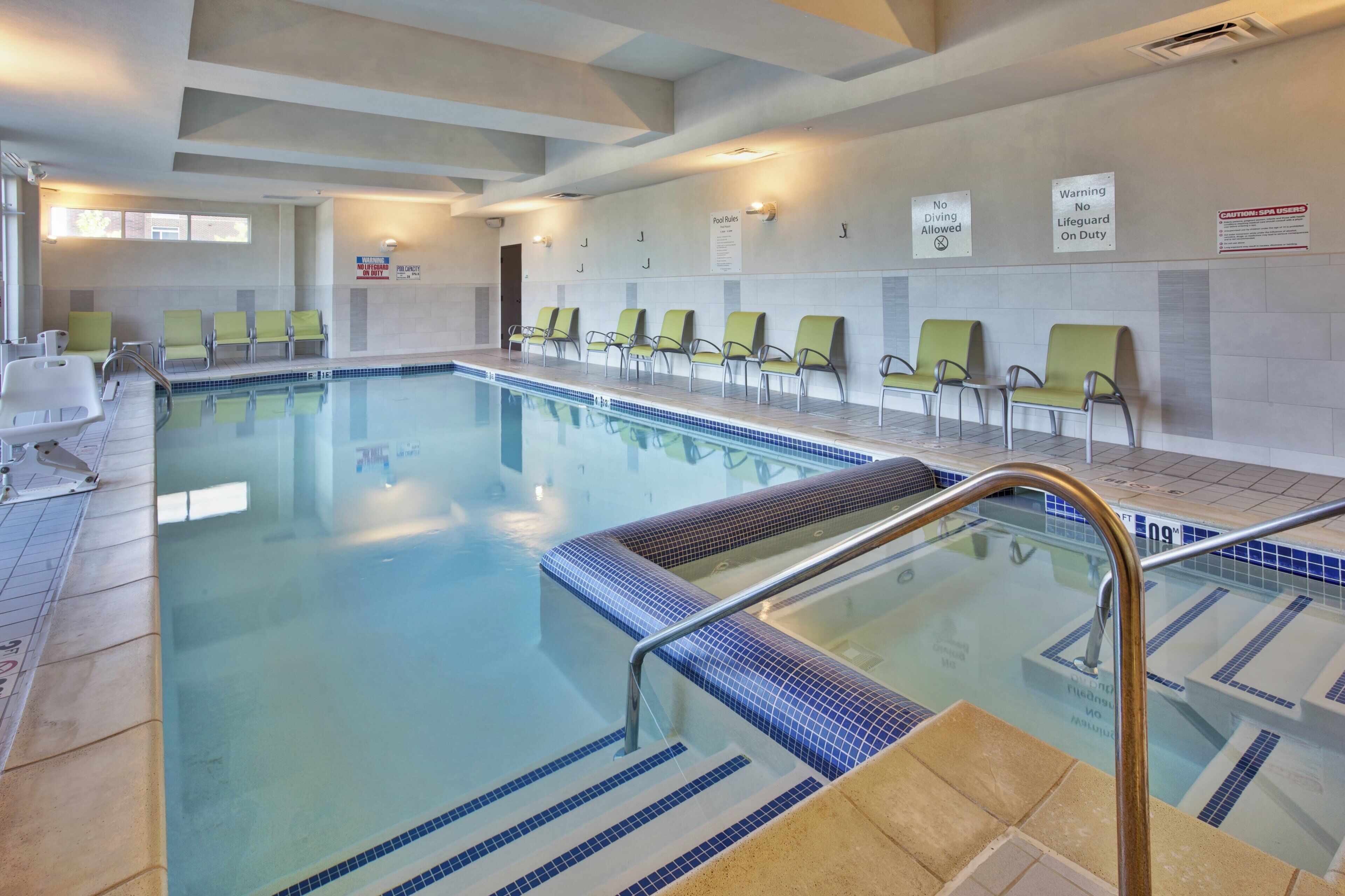 Una piscina con borde de azulejos, un cartel de prohibido bucear y un aviso de ausencia de salvavidas.