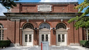 A historic building with a brick facade, three arched windows, and a central entrance with a signboard. - Holiday Inn Detroit Metro Airport by IHG (Romulus)
