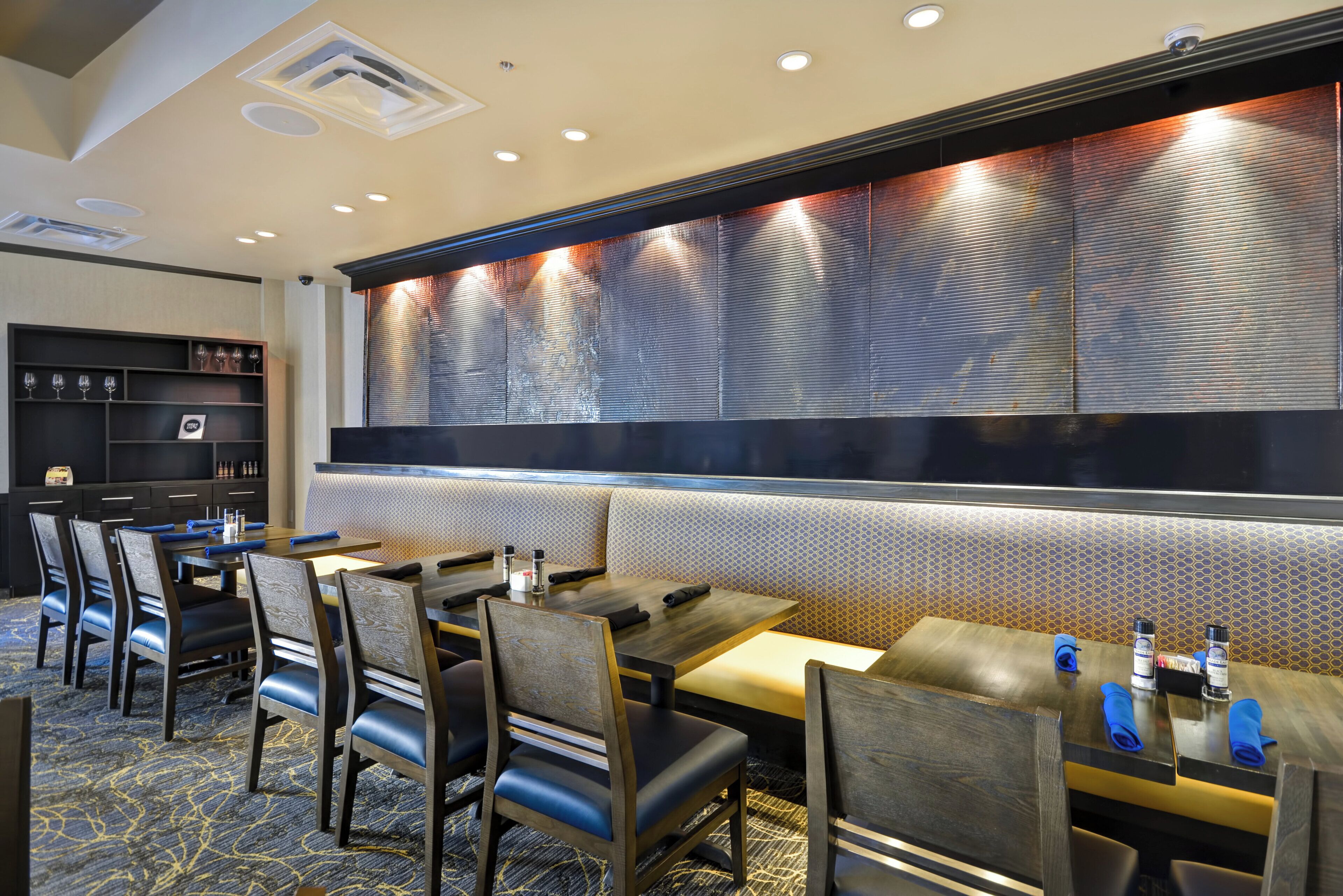 Un comedor de hotel con una barra larga, varias mesas y sillas.