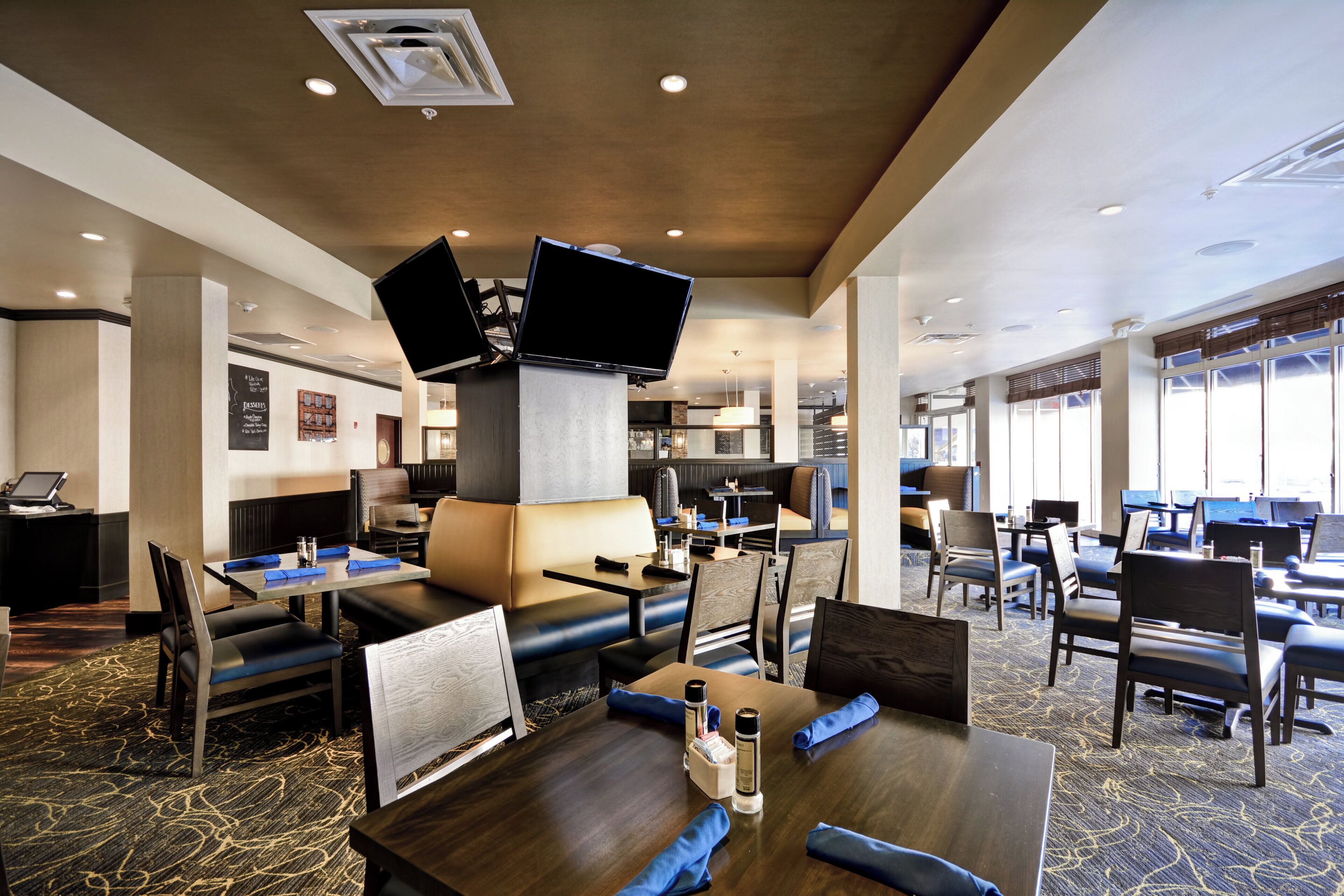 A hotel lobby with seating areas, a reception desk, and a large screen.