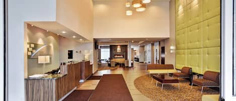 A hotel lobby with a reception desk, seating area, and a fireplace.