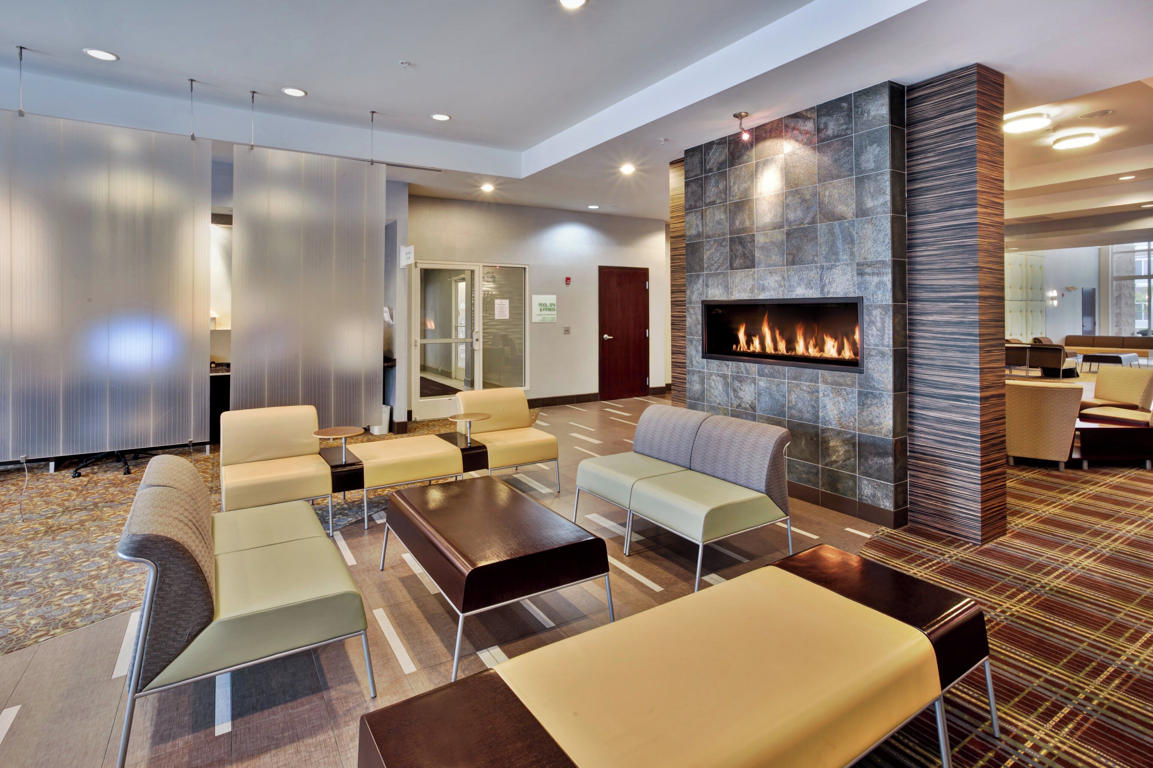 A hotel lobby with a fireplace, seating area, and a reception desk.