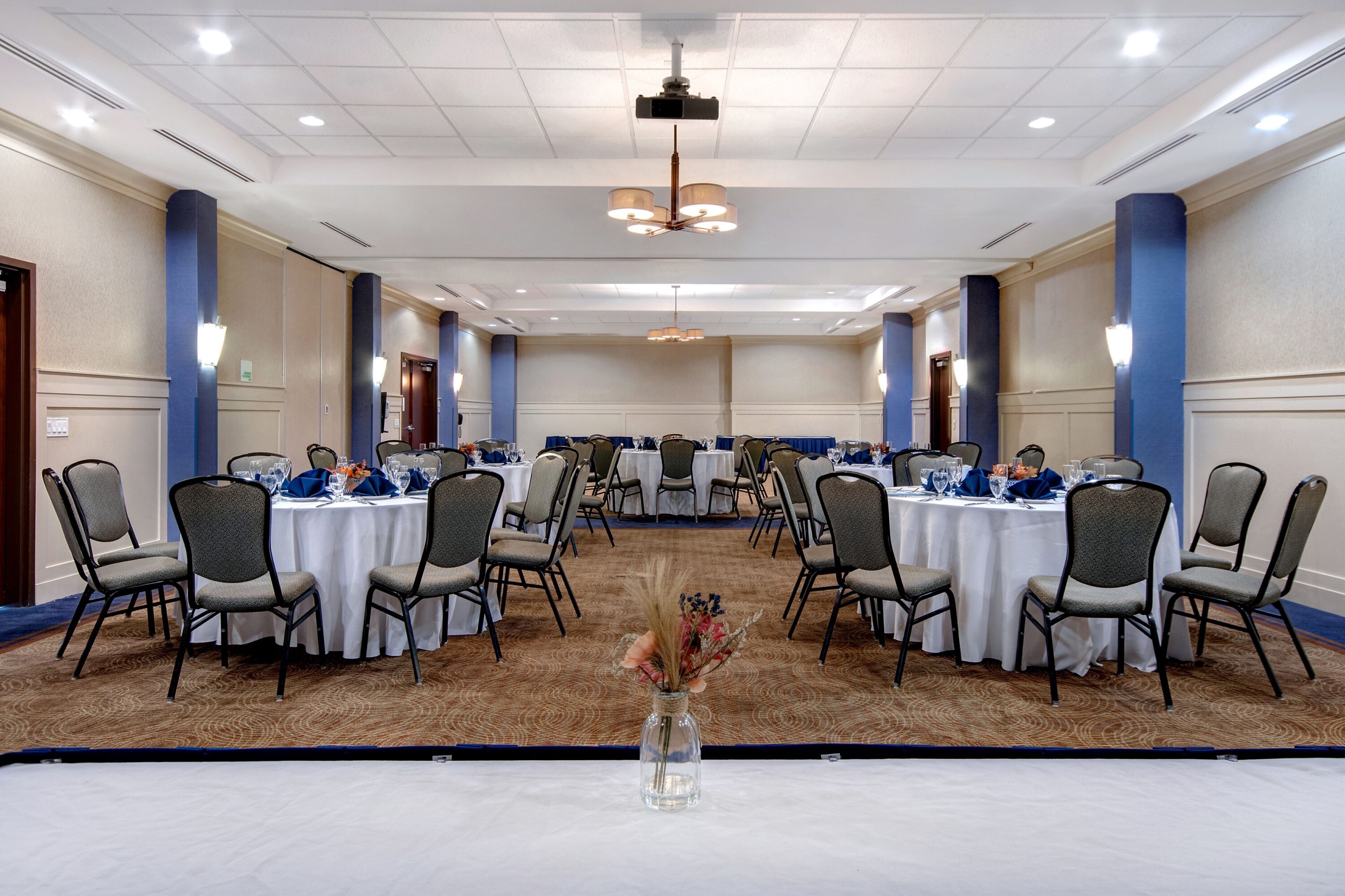 A conference room with round tables, chairs, and a ceiling-mounted projector.